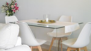 A modern dining area with a glass table, white chairs, and a decorative vase with flowers.