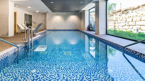 An indoor swimming pool with a tiled floor and a glass barrier.