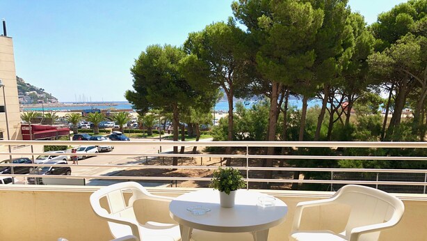 Un balcon avec des chaises en plastique blanches et une petite table sur laquelle est posée une plante en pot.