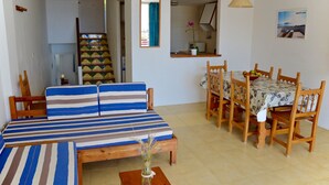 Un salon comprenant un canapé, une table à manger et des chaises. Un escalier mène à une autre pièce.