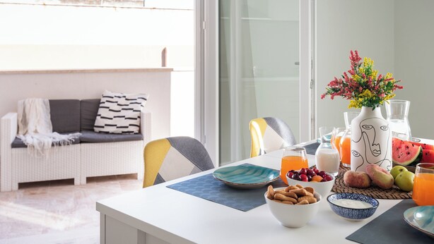 Un'area pranzo con un tavolo apparecchiato per la colazione, con frutta, dolci e bevande.