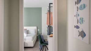 Una camera d'albergo con un letto, una sedia, una scrivania e un quadro raffigurante pesci.