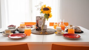 Una tavola imbandita per la colazione, con piatti, ciotole, un vaso di girasoli e diversi cibi per la colazione.
