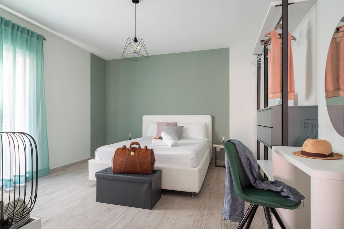 Une chambre à coucher moderne, comprenant un lit, un bureau, une chaise, un luminaire suspendu et une armoire.