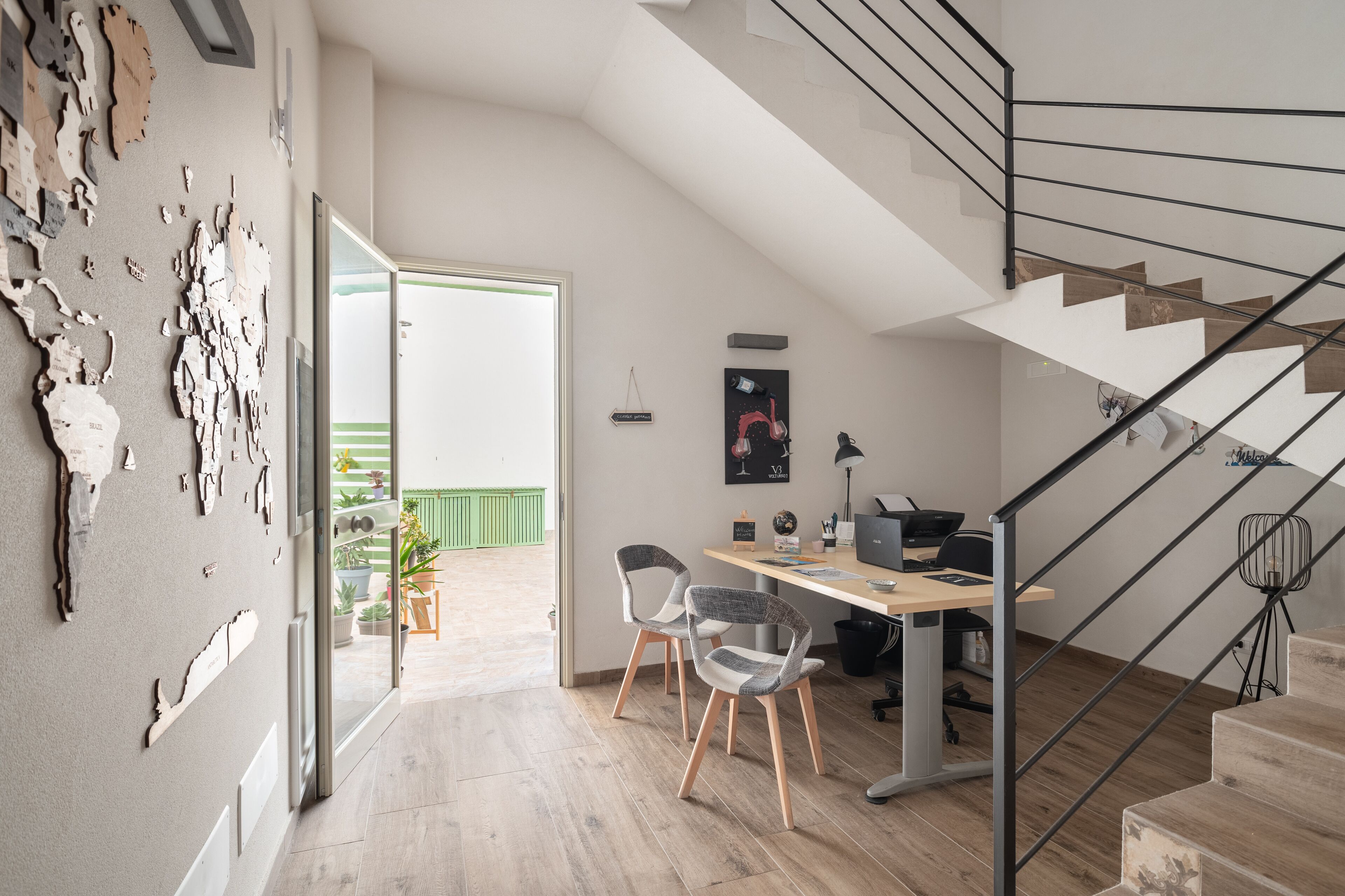 Un interior moderno con una escalera, un escritorio con ordenador y vistas al exterior.