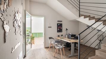 Un interior moderno con una escalera, un escritorio con ordenador y vistas al exterior.