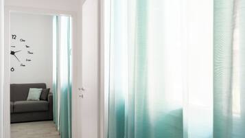 Un pasillo con un reloj en la pared, un sofá y cortinas color turquesa.