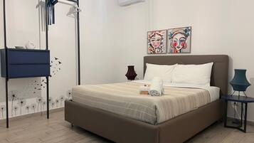 Quarto com cama, cómoda, candeeiro e duas pinturas na parede.