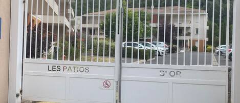 Un cancello conduce a un'area residenziale, con un cartello che riporta 'LES PATRIOS' e il simbolo di parcheggio per disabili.