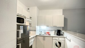 A compact kitchen with a microwave, oven, dishwasher, and a coffee maker. - Charming 1BR Apt with Large Terrace, A/C, WiFi, Near Town Center & Spa, Pet-Friendly! (Lamalou-les-Bains)