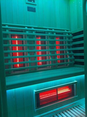 Una sauna con interior de madera y rejilla metálica.