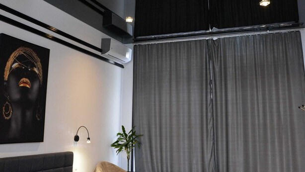 Ein modernes Schlafzimmer mit einem großen Bett, einem Nachttisch, einer Lampe und einer Deckenleuchte.