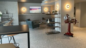 A modern interior with a dining area, seating, a decorative metal sculpture, and a wall-mounted screen. - Hotel Restaurant zur Sonne (Sissach)