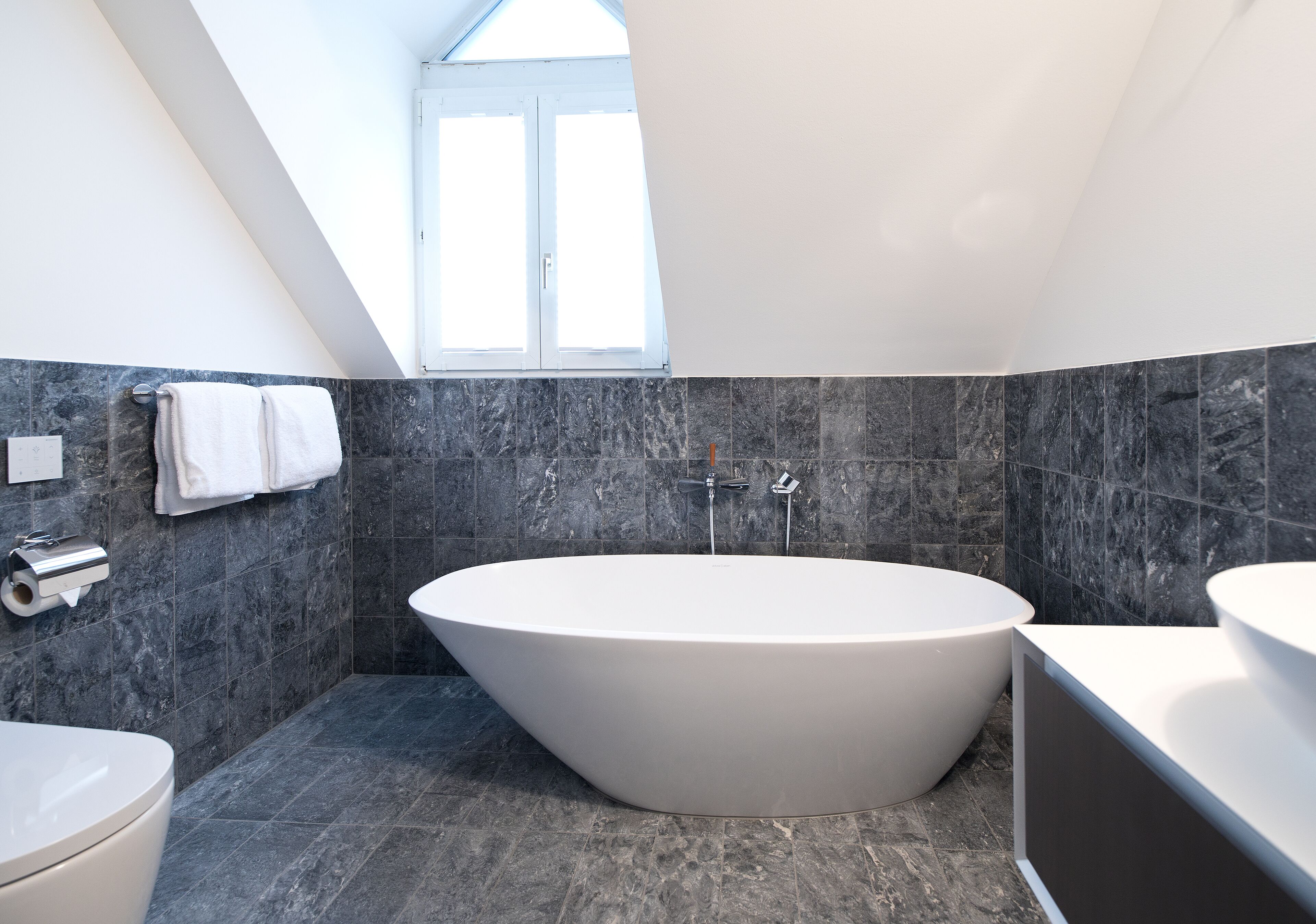 Ein modernes Badezimmer mit freistehender Badewanne, Toilette und Waschbecken.