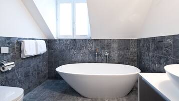 Ein modernes Badezimmer mit freistehender Badewanne, Toilette und Waschbecken.