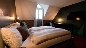 A bedroom with a bed, pillows, a nightstand, a TV, and a window. - Hotel Restaurant zur Sonne (Sissach)