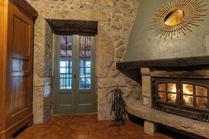 A stone-walled room with a wooden door, a fireplace, and a sunburst decoration on the wall. - Maisons des Fleurs, villa with pool in northern Portugal (Sande)