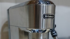 A De'Longhi espresso machine with a metallic finish, a digital display, and a black handle.
