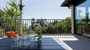 Ein Balkon mit Tisch, Blumentöpfen und einem Glasbehälter mit Blumen.