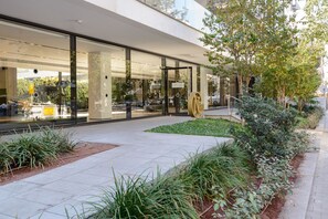 A modern building with large glass windows, a well-maintained garden, and a clear pathway. - High End & City View by FeelHome (Tel Aviv)