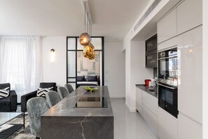 A modern kitchen with a central island, built-in oven, and a dining area with chairs and a table. - High End & City View by FeelHome (Tel Aviv)