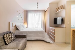 A modern bedroom with a bed, a sofa, a TV, and a wooden cabinet.