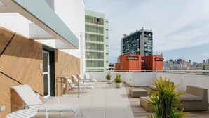 Une terrasse sur le toit, aménagée avec des chaises longues, des plantes en pot et offrant une vue sur le paysage urbain.