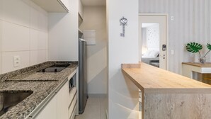 Une cuisine moderne dotée de plans de travail en granit, d’un réfrigérateur en acier inoxydable et d’un four encastré.