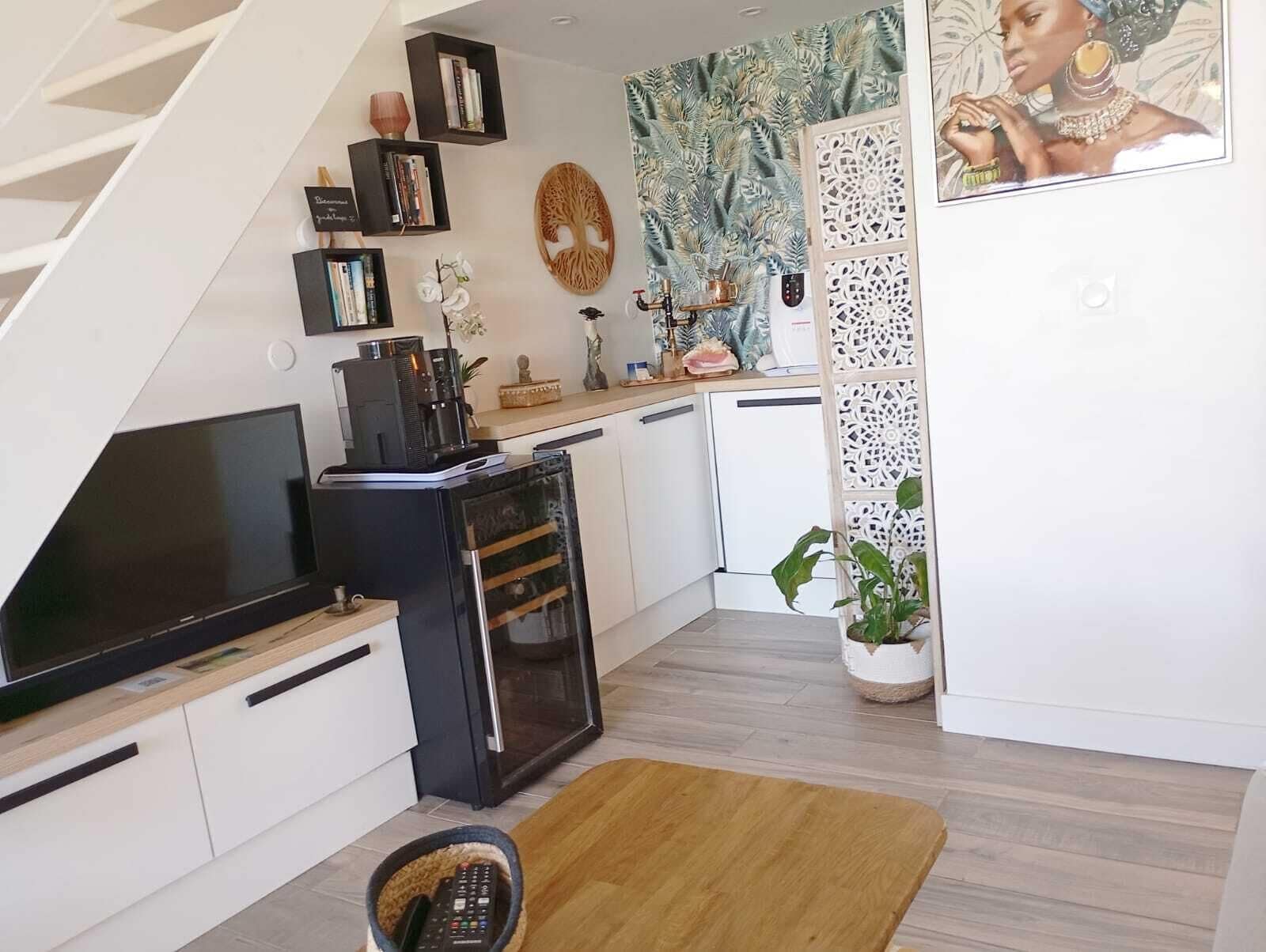 Eine moderne Küche mit Einbauofen, Kaffeemaschine und Fernseher. Eine Treppe führt zu einer weiteren Ebene.