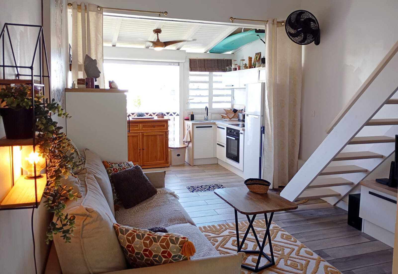 Een gezellige woonkamer met een bank, een kleine tafel en een trap naar een keukenhoek.