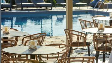 A poolside area with wicker chairs and tables, some with candles.