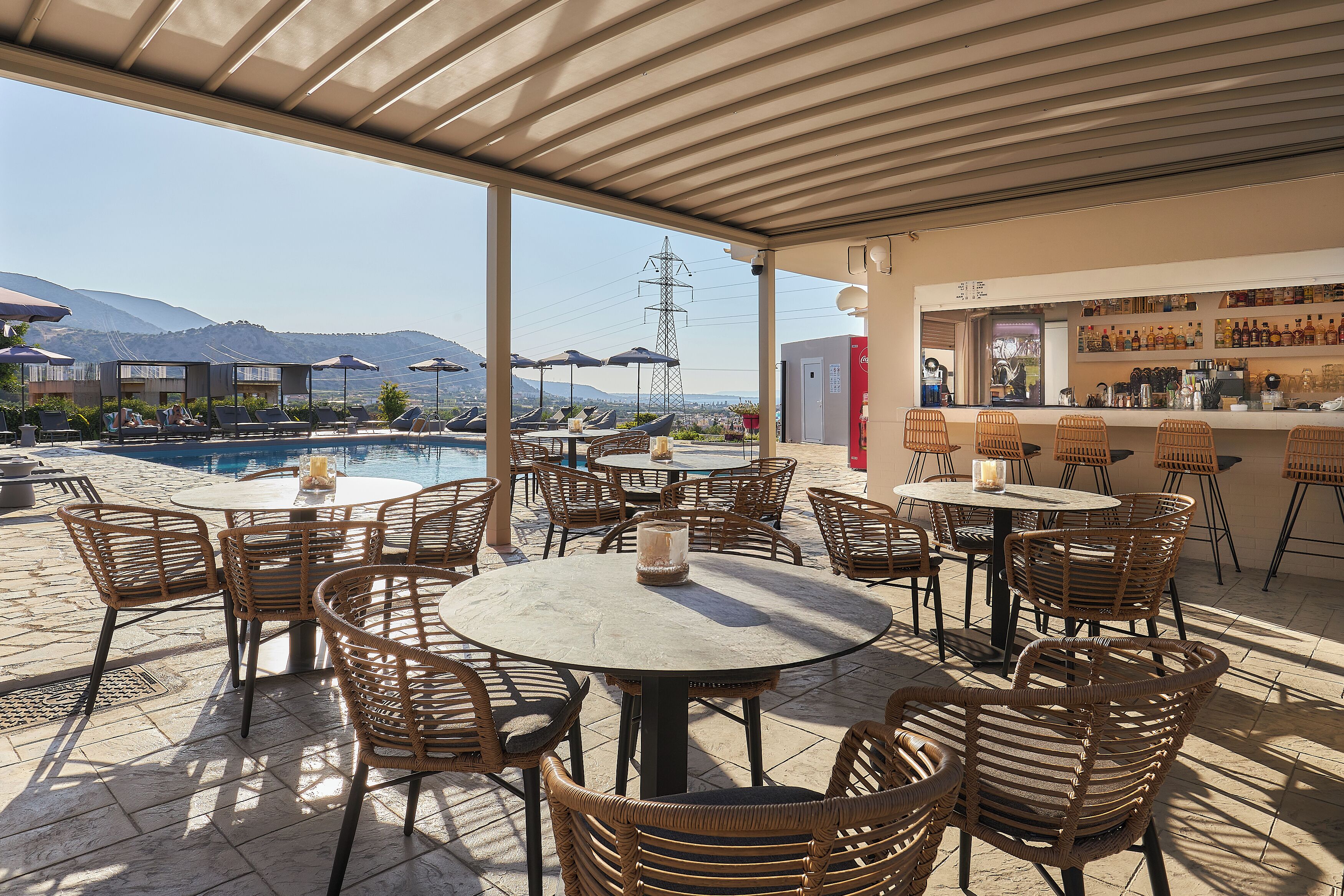 A rooftop bar with outdoor seating and a pool view.