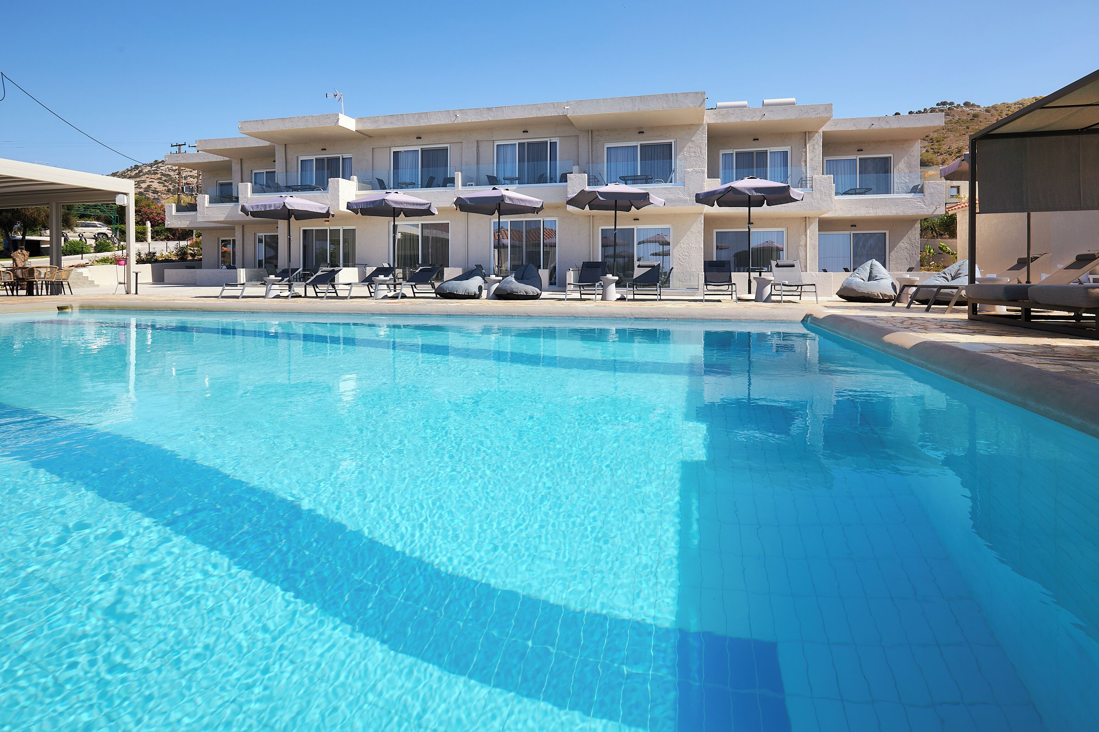 Ein Hotel mit Schwimmbad, Liegestühlen und Sonnenschirmen.