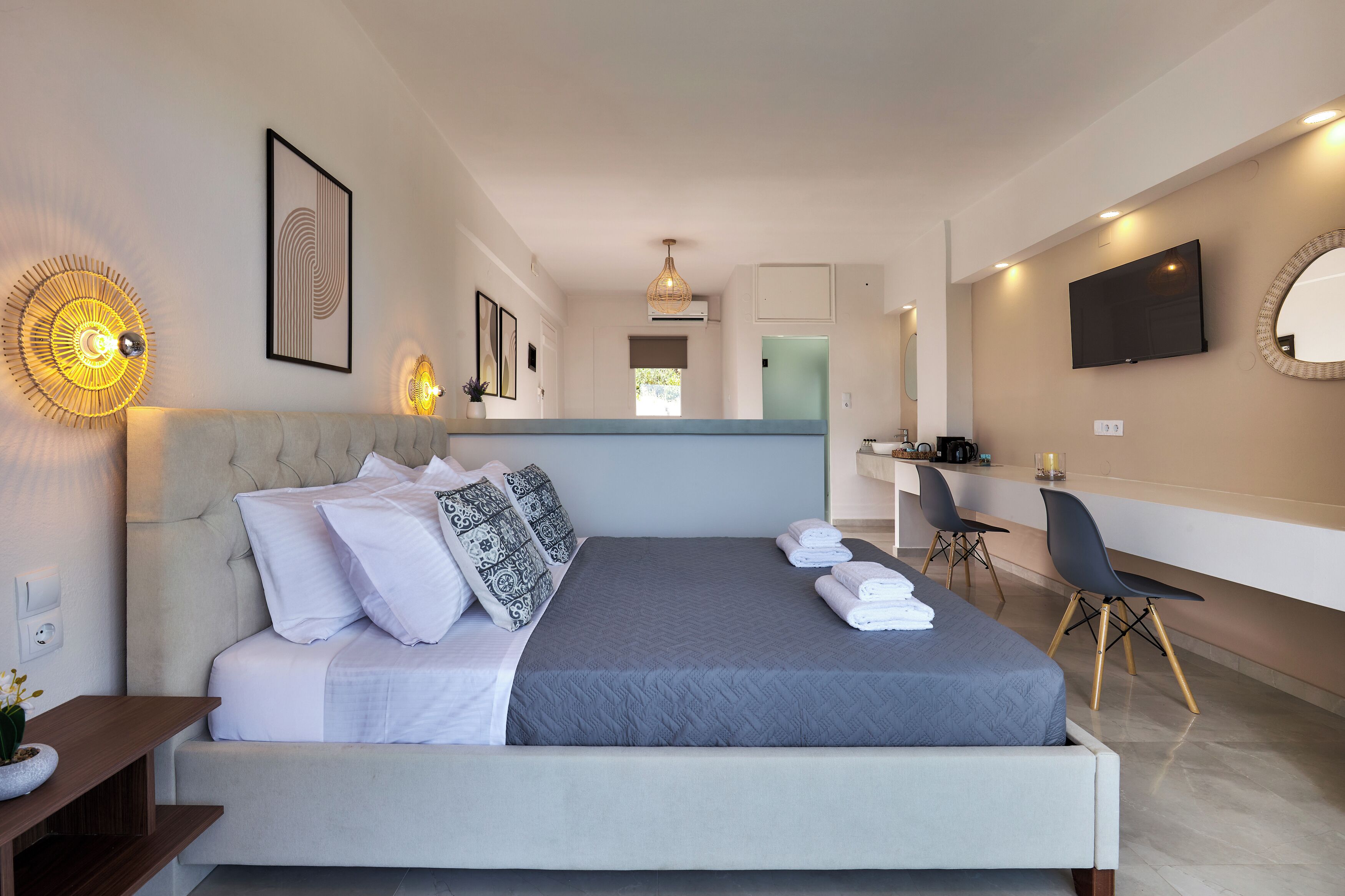 A modern hotel room with a large bed, a desk, and a TV.