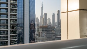 Un immeuble de grande hauteur doté d’une façade moderne en verre, entouré d’autres bâtiments imposants, dont un gratte-ciel particulièrement remarquable en arrière-plan.