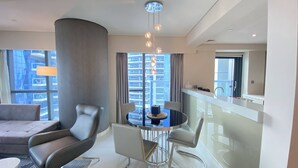 Une chambre d’hôtel moderne dotée d’un coin repas, d’un canapé, d’une table ronde et offrant une vue sur le paysage urbain.