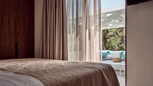 A bedroom with a large bed, a wooden wardrobe, and a view of an outdoor seating area.