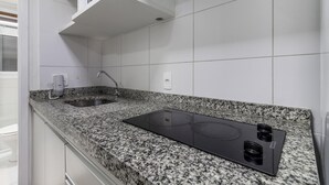 A kitchen with a granite countertop, stainless steel sink, and a black electric stove. - Av1110 Studio Avanhandava (São Paulo)