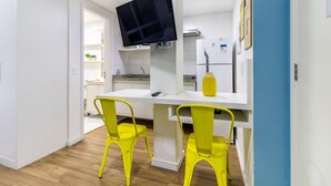 A compact kitchen with white cabinets, a built-in stove, and a flat-screen TV mounted above the counter. - Av1110 Studio Avanhandava (São Paulo)