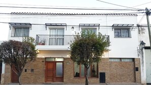 A two-story building with a wooden door, a balcony, and a brick facade. - Hostal Tilian (Salta)
