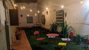 A courtyard with a tiled pathway, outdoor seating, string lights, and potted plants. - Hostal Tilian (Salta)