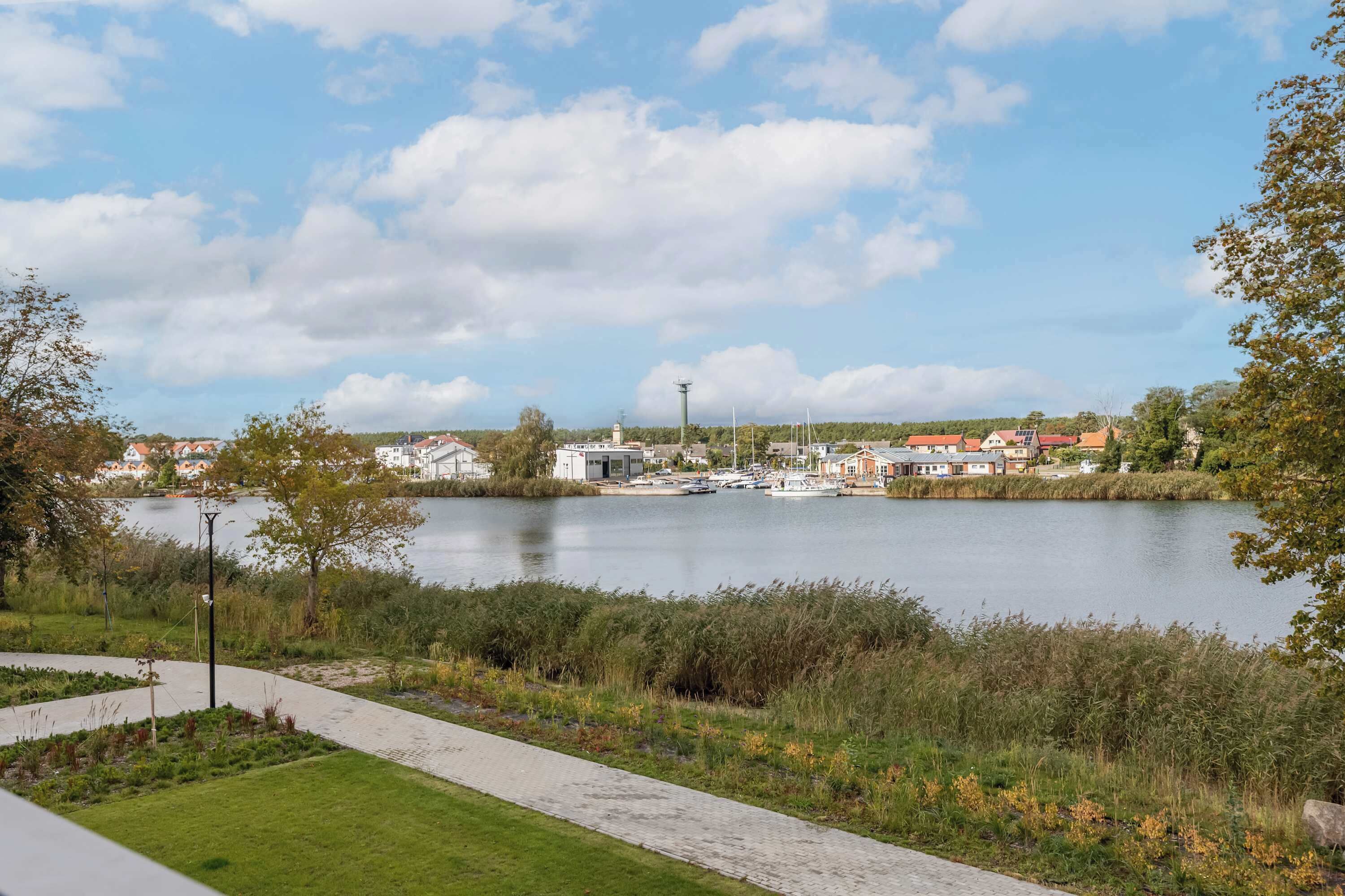 Une vue sur le bord de la rivière, avec une promenade pavée, des bâtiments en arrière-plan et un ciel dégagé.