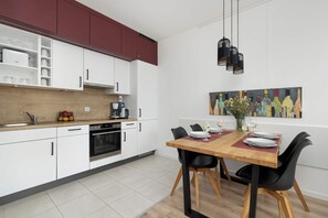 A modern kitchen with white cabinets, a wooden countertop, and a dining area with a wooden table and black chairs.