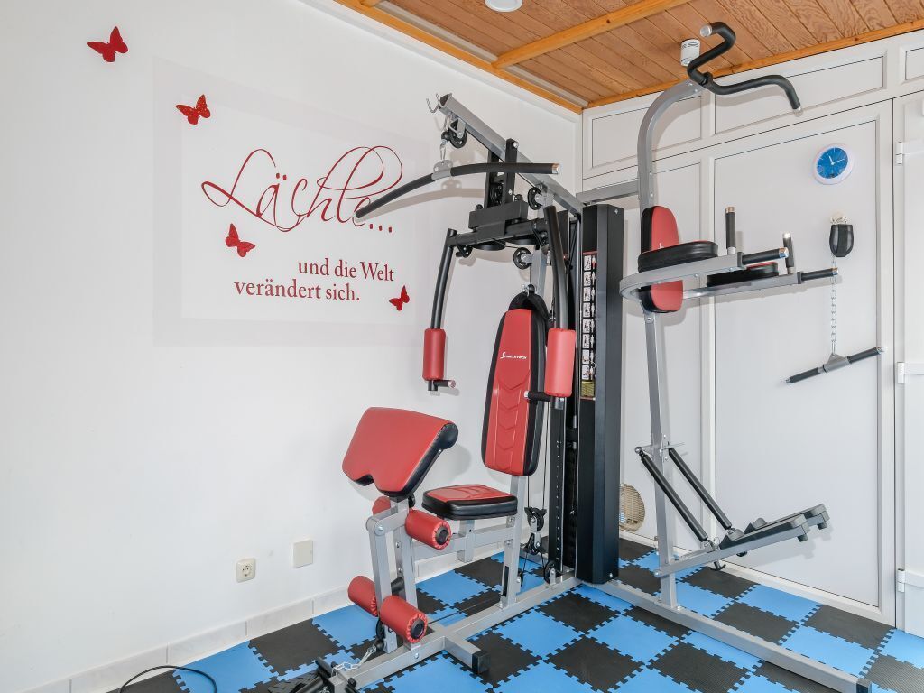 Ein Fitnessraum mit Trainingsgeräten, einer Wand mit motivierenden Texten und einer blauen und schwarzen Yogamatte.