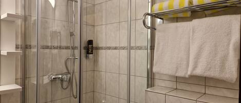 A modern bathroom with a glass-enclosed shower, a towel rack with striped towels, and a soap dispenser.