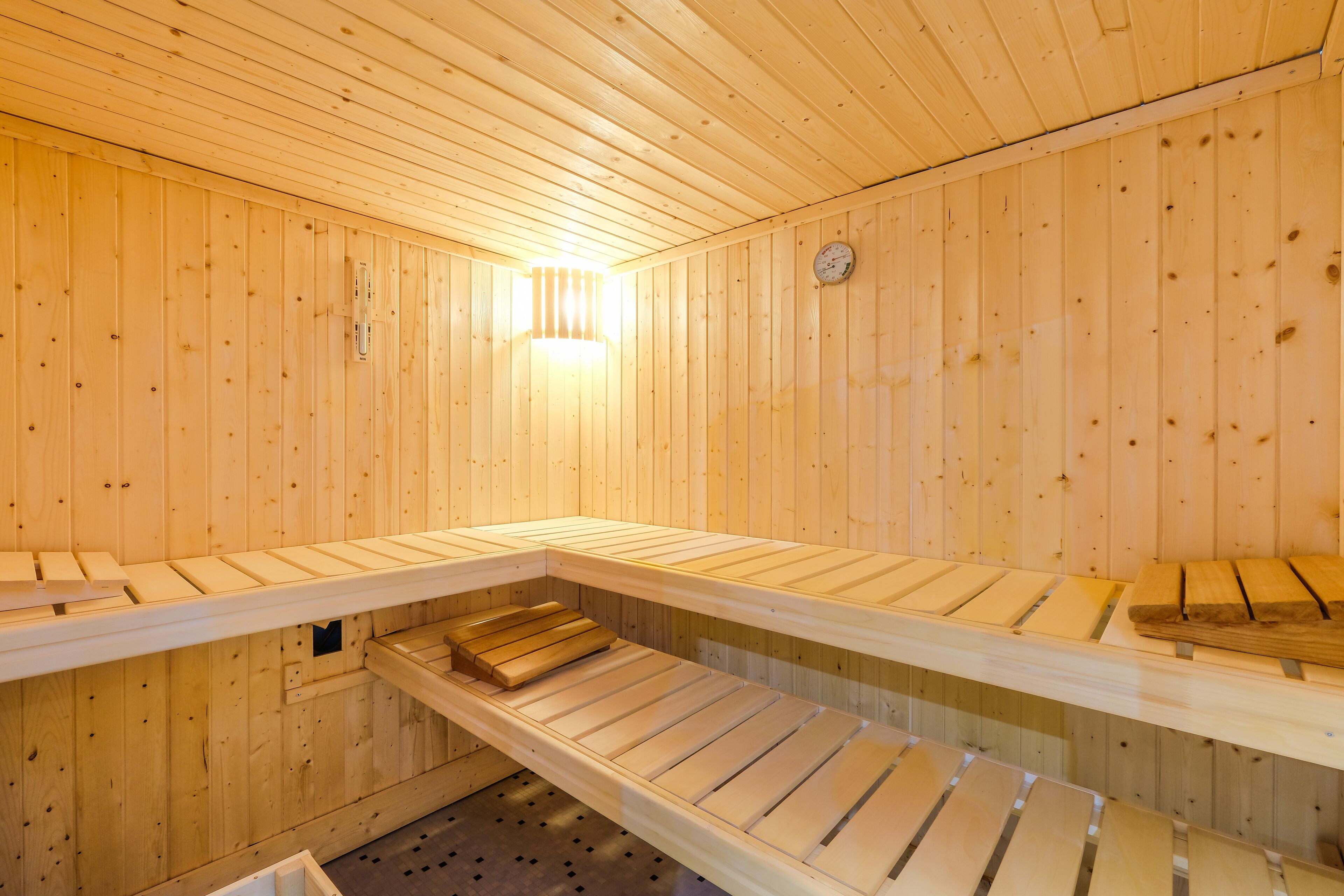 Een sauna met houten banken en een zichtbare lamp.