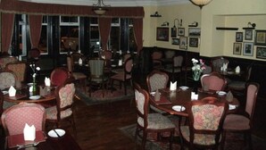 A dining area with round tables and chairs, framed pictures on the walls, and a chandelier. - The Clarkes Hotel (Barrow-in-Furness)