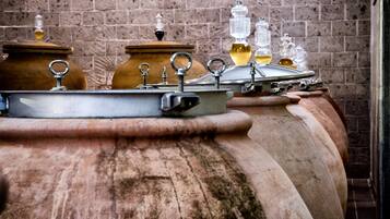 A row of large, rustic wine barrels with metal lids and handles, set against a brick wall background.