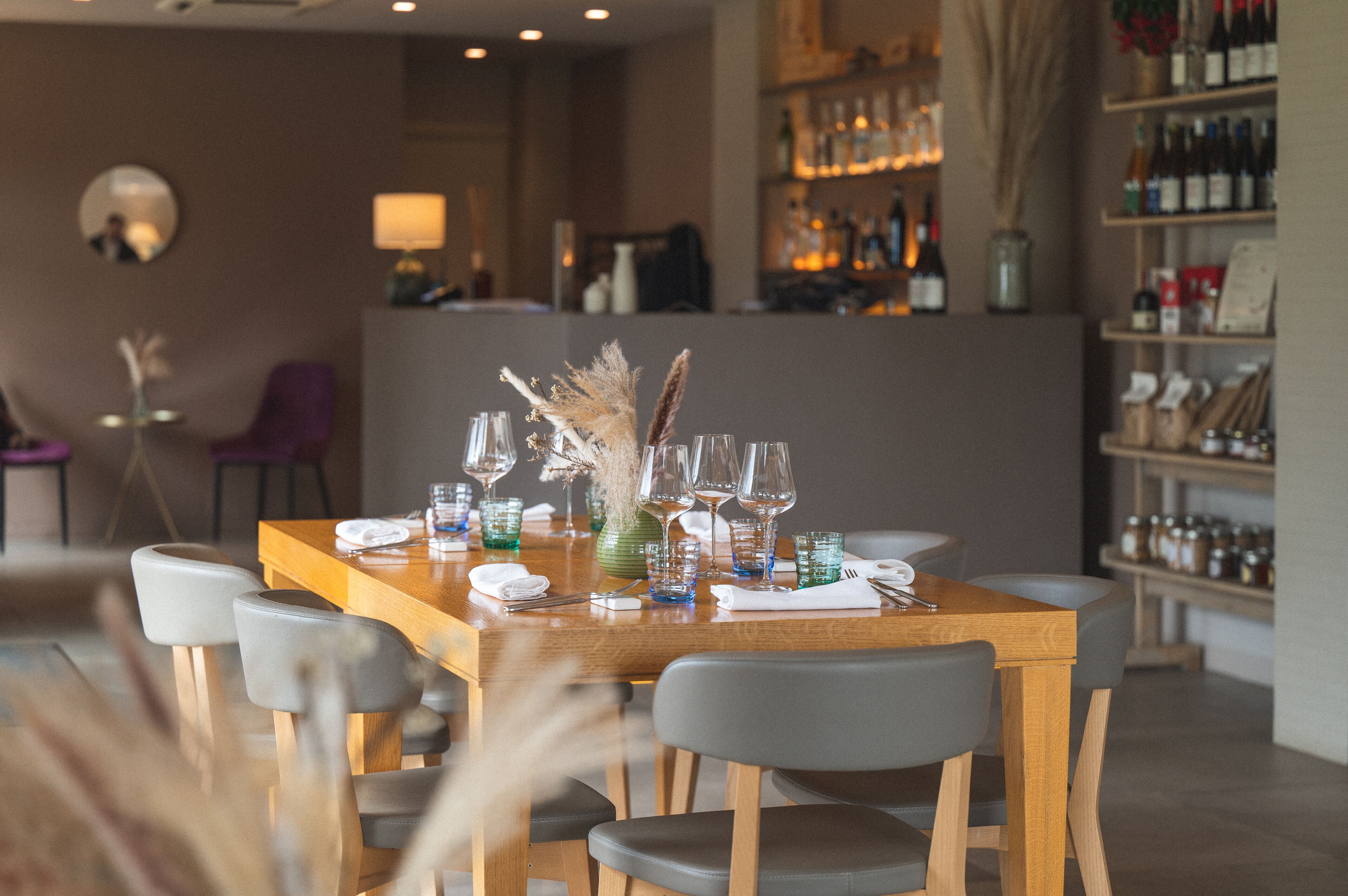 Ein Restaurant mit Holztisch, gedecktem Esstisch, Stühlen und einer Theke im Hintergrund.