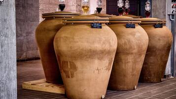 Grote terracotta plantenbakken met labels, een betegelde vloer en een bakstenen muur op de achtergrond.